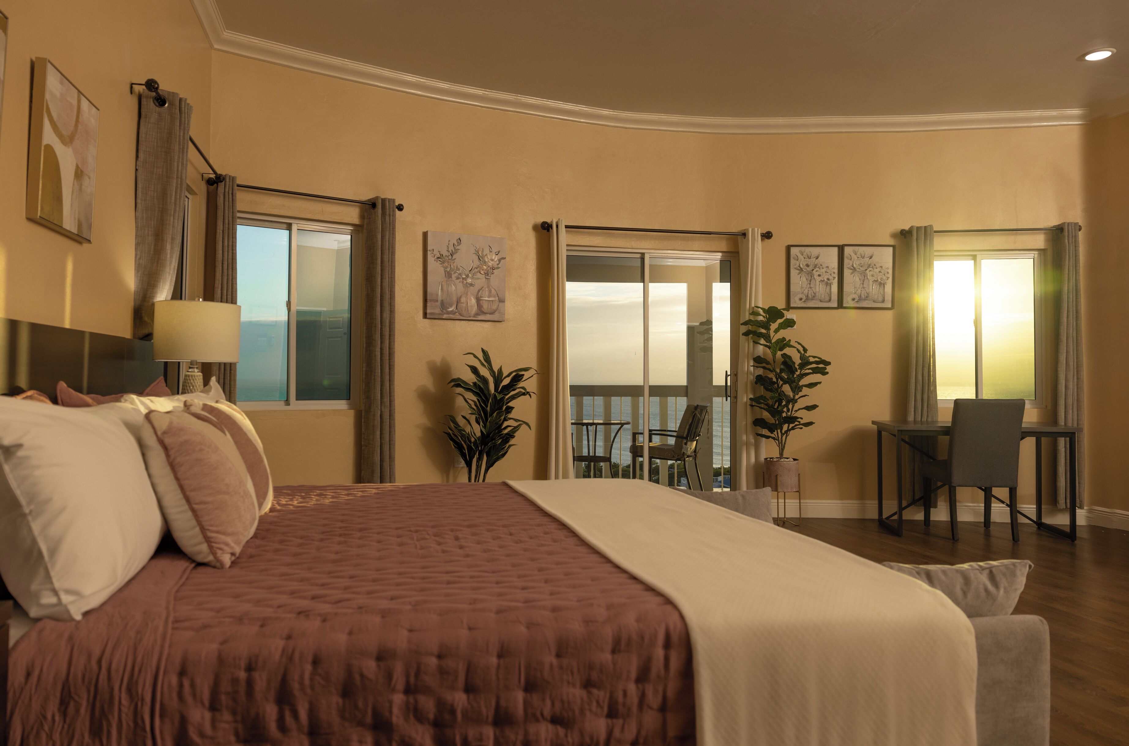 Ein Hotelzimmer mit einem großen Bett, einem Schreibtisch und einem Balkon mit Blick.