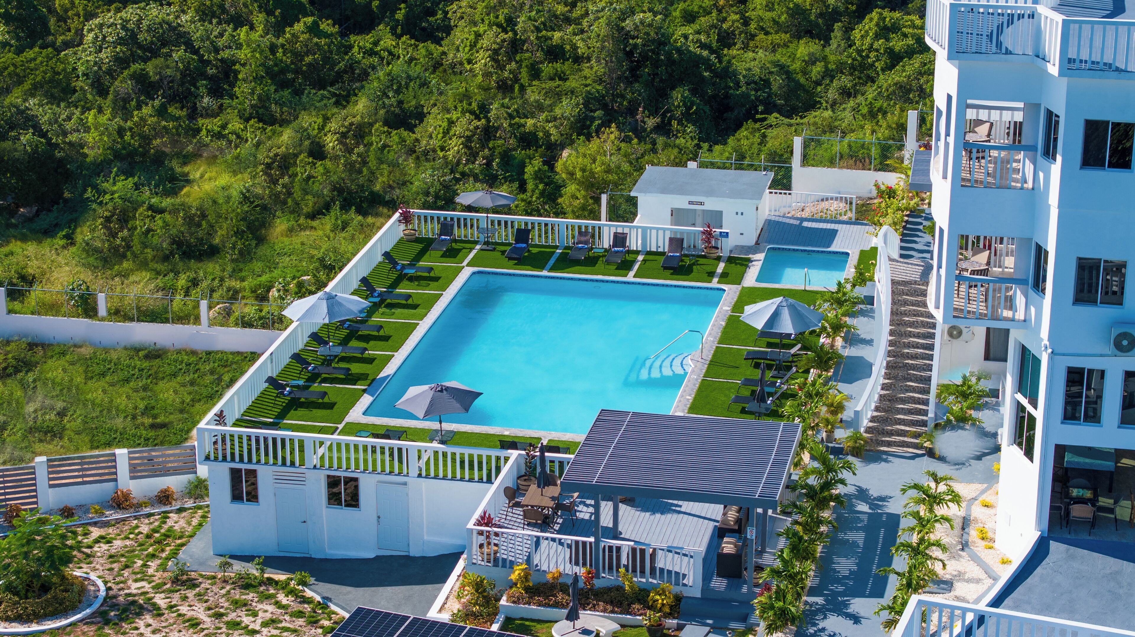 A resort with a large central pool, multiple sun loungers, and a covered patio area.