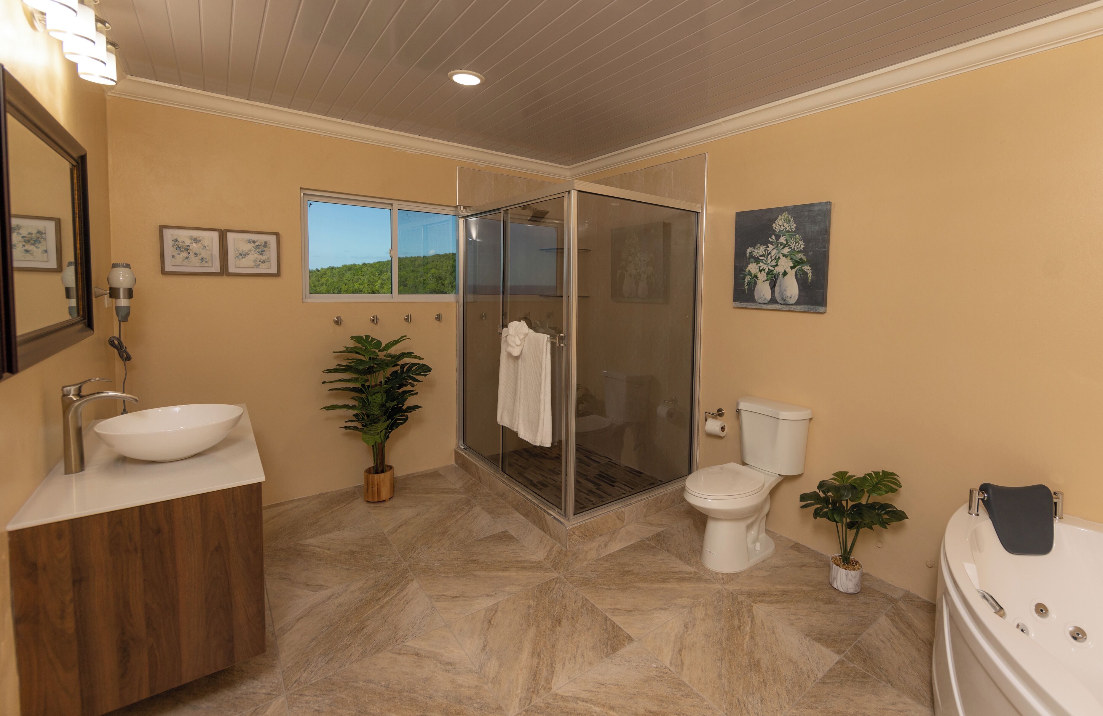 Un baño moderno con ducha de vidrio, lavamanos amplio, inodoro y bañera.