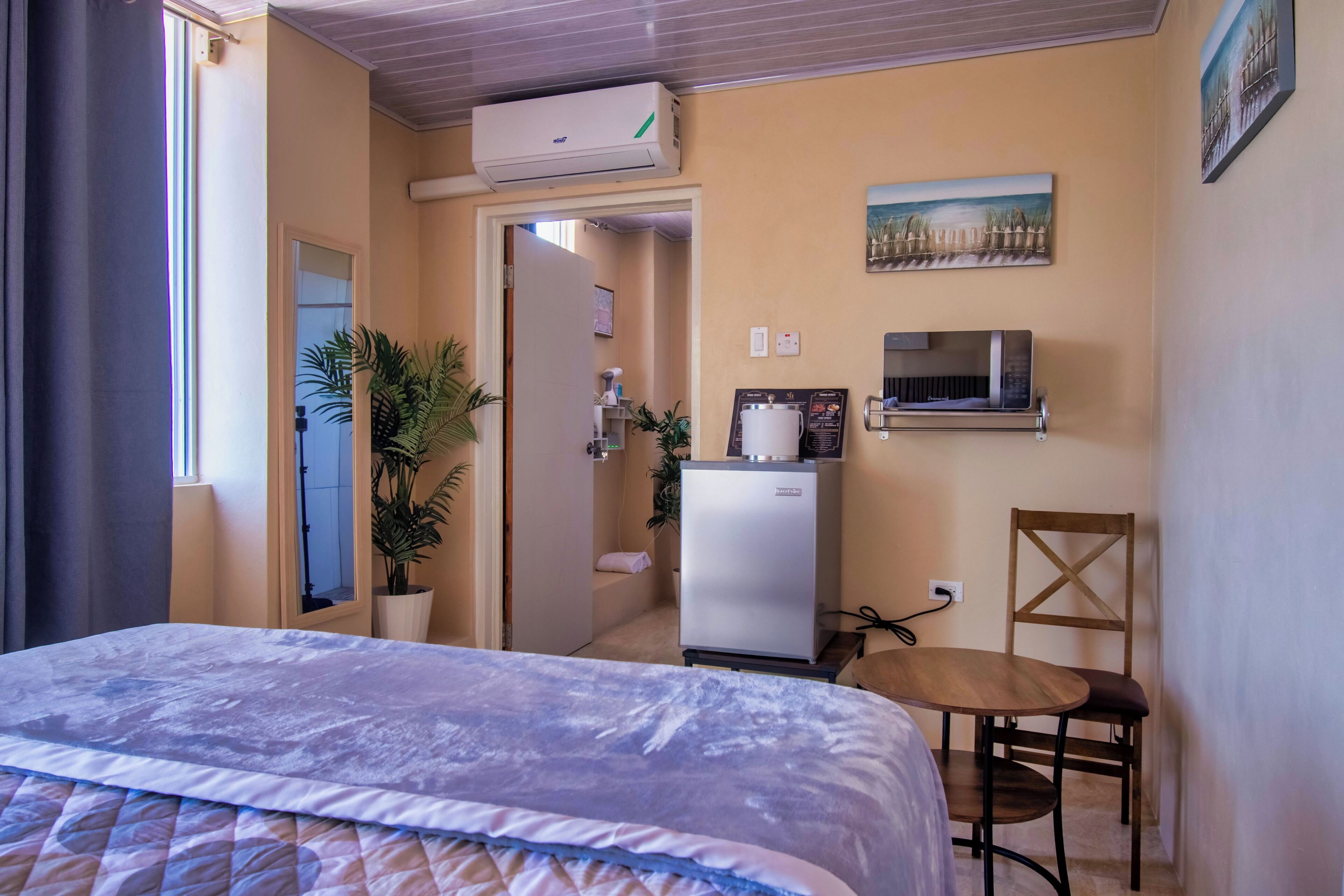 Una habitación de hotel con cama, escritorio, silla, refrigerador y microondas.