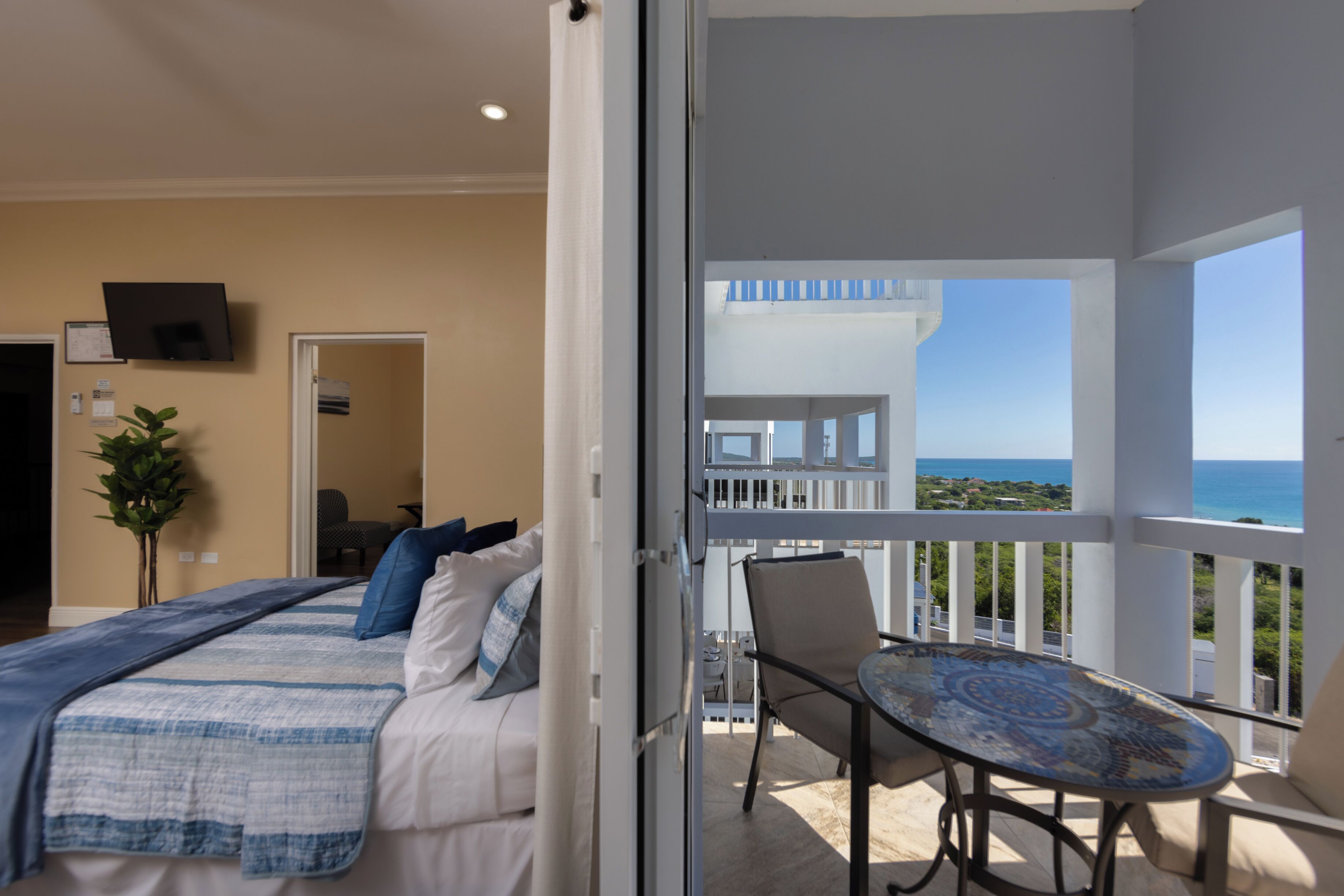 Un dormitorio con cama, una silla y un balcón con vista al océano.
