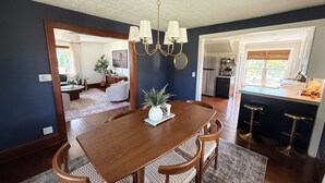 Un coin repas avec une table et des chaises en bois, un lustre et une vue sur la cuisine.