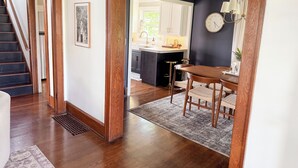 Une cuisine moderne aux murs sombres, avec une table à manger en bois et un escalier menant à une autre pièce.