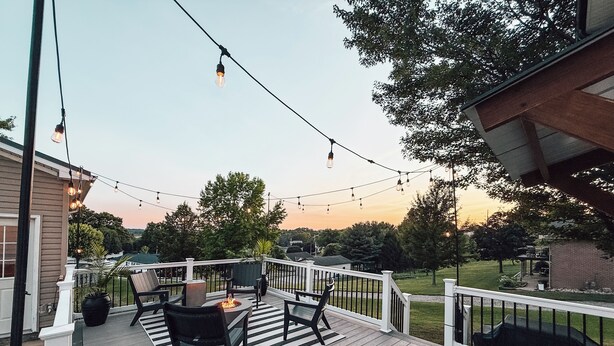 Une terrasse en bois, dotée de meubles d’extérieur et illuminée de guirlandes lumineuses.