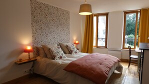 A bedroom with a bed, two bedside lamps, a window with curtains, and a radiator. - Village house in the Perche (Le Mage)