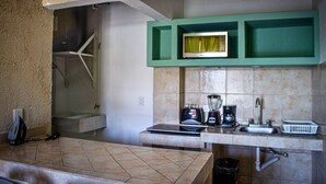 Una cucina con forno a microonde, frullatore, macchina del caffè e lavello.