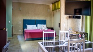 Una camera d'albergo con un letto, una TV, un tavolo con sedie e una finestra con tende.