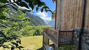 Un edificio in legno con parete in pietra, un balcone in legno e vista su un paesaggio montuoso.