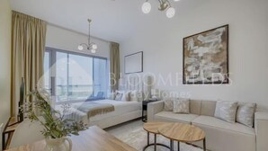 A modern hotel room with a large window, a sofa, a coffee table, and a painting on the wall.