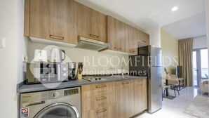 A modern kitchen with wooden cabinets, a built-in washing machine, and a dining area with a table and chairs.