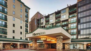 Entrada d'un hotel Sheraton amb diverses plantes, balcons i façana de pedra.