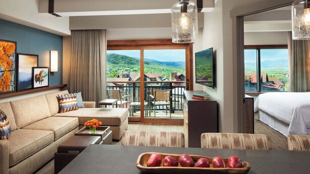 Habitació d'hotel amb sofà, taula de menjador i vista a la pagesia.