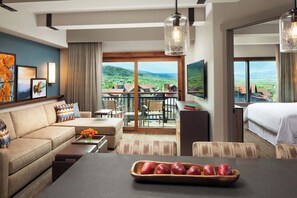Habitación de hotel con sofá, mesa de comedor y vista al campo.