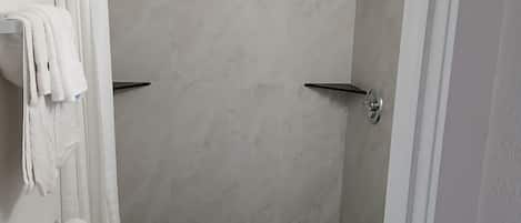 A bathroom with a shower, toilet, and towel rack.