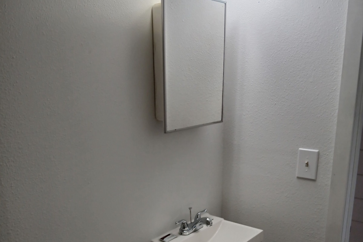 A small, white bathroom with a toilet, sink, and mirror.