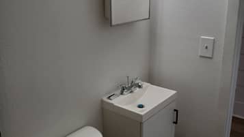 A small, white bathroom with a toilet, sink, and mirror.