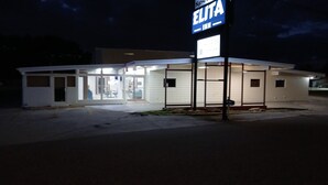 Ein kleines, eingeschossiges Gebäude mit einem Schild für 'ELITA INN' und einem sichtbaren Eingang.