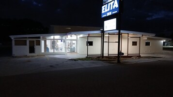 Um pequeno edifício térreo com uma placa indicando 'ELITA INN' e uma entrada visível.