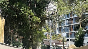 A concrete staircase with metal railings, surrounded by greenery and a building with balconies in the background. - Beautiful penthouse with a view. (Florianópolis)
