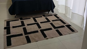 A room with a bed, a patterned rug, a white air conditioning unit, and white curtains. - Beautiful penthouse with a view. (Florianópolis)