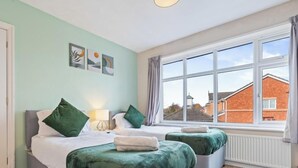 Ein Schlafzimmer mit zwei Betten, einem Fenster mit Blick auf Gebäude und Kunstwerken an der Wand.