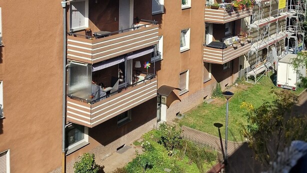 A multi-story residential building with balconies, a garden area, and a construction site nearby. - Cozy and enjoyable apartment in Essen for a relaxing getaway (Essen)