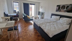 A hotel room with a bed, a desk, a chair, a TV, and a painting on the wall. - Cozy and enjoyable apartment in Essen for a relaxing getaway (Essen)