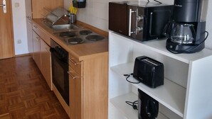 A compact kitchen with wooden cabinets, a built-in oven, a coffee maker, and a toaster. - Cozy and enjoyable apartment in Essen for a relaxing getaway (Essen)