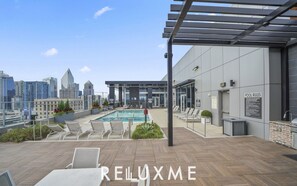 A rooftop pool area with lounge chairs, a pool, and a city view. - Reluxme Luxury 2BR | Walk to Stadiums & Convention Center (Charlotte)