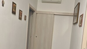 Tummanvärisellä laattalattialla, valkoisilla seinillä ja puisella ovella varustettu käytävä.