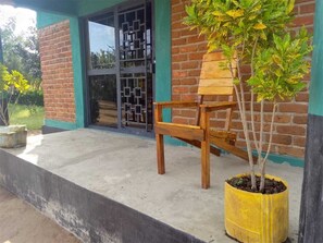 A wooden chair outside a building with a brick wall and a metal gate.
