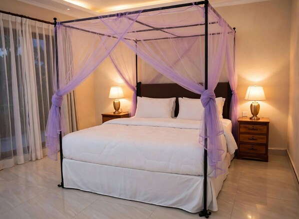 A four-poster bed with a canopy, two bedside tables with lamps, and a large window with sheer curtains.