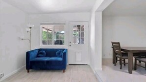 A room with a blue sofa, a dining table with chairs, and a white door with glass panels. - House in Cozy Old Town Scottsdale with AC, Pool Table, Central Location (Scottsdale)
