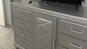 A grey cabinet with a flat-screen TV on top, a mirrored cabinet door, and a small remote control on the TV stand. - House in Cozy Old Town Scottsdale with AC, Pool Table, Central Location (Scottsdale)