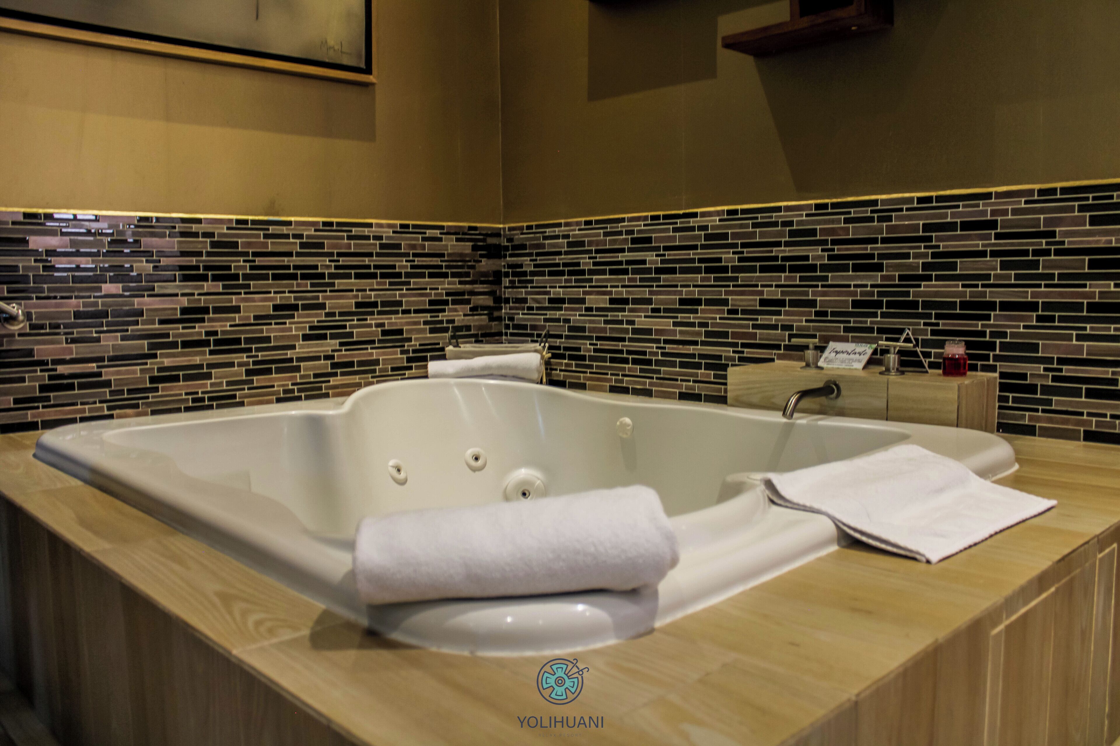 A modern bathroom with a large bathtub, a wooden vanity, and a tiled backsplash.