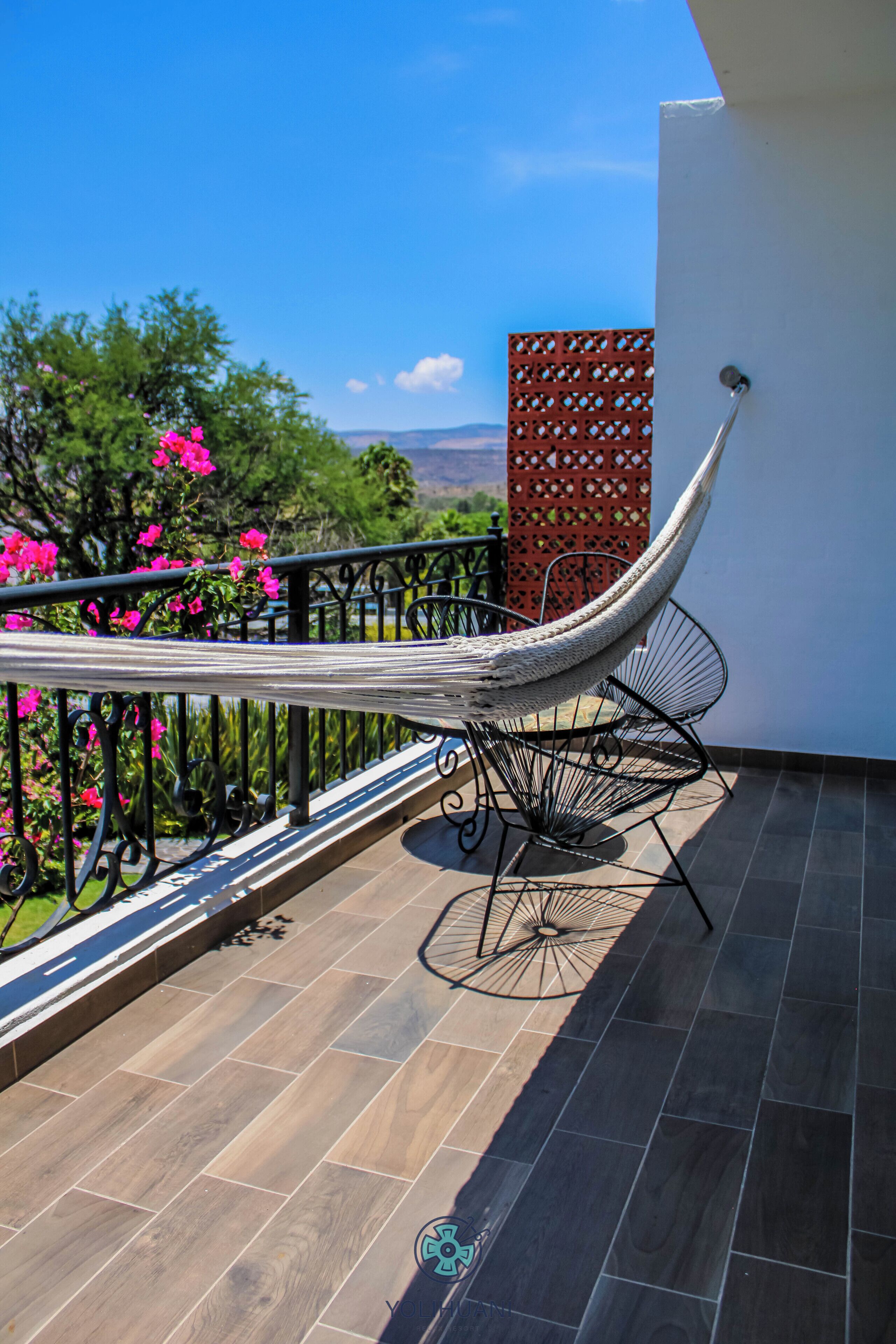 Una silla hamaca en un balcón con vistas al paisaje.