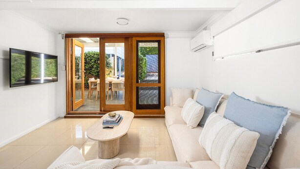 A modern living room with a sofa, a coffee table, and a TV. - La Luce - Coastal Retreat in Port Stephens (Corlette)
