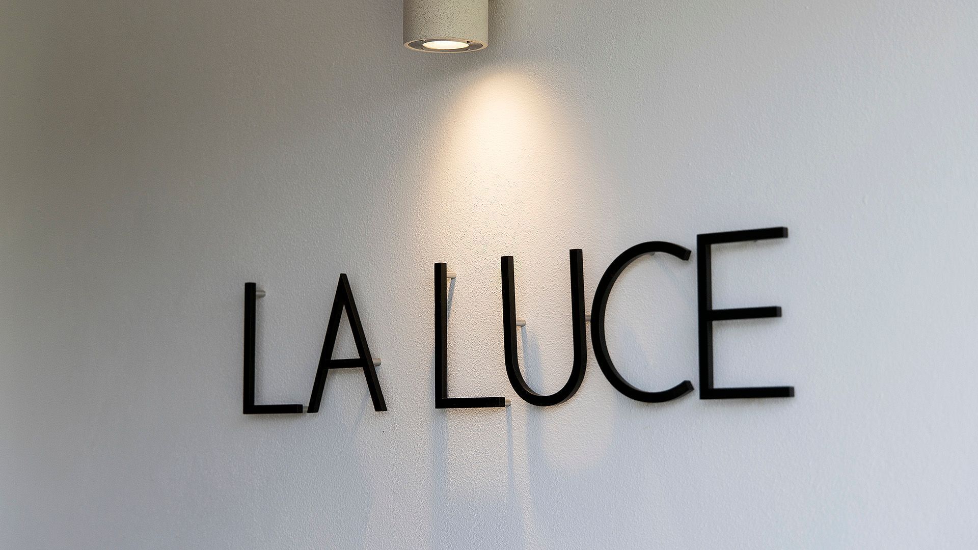 Una pared con el texto 'LA LUCE' en una tipografía moderna y sin serifa.