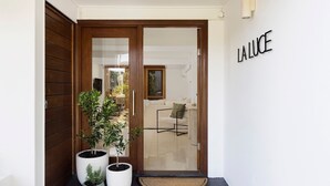 A wooden door with a glass panel, potted plants, and a wall sign reading "LA LUCE". - La Luce - Coastal Retreat in Port Stephens (Corlette)