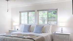 A bedroom with a bed, two bedside tables, two windows, and a ceiling fan. - KING Bed+Cozy Farmhouse Cottage+Close to Trails (Bella Vista)
