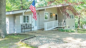 A single-story house with a porch, an American flag, and a number 17 sign. - KING Bed+Cozy Farmhouse Cottage+Close to Trails (Bella Vista)
