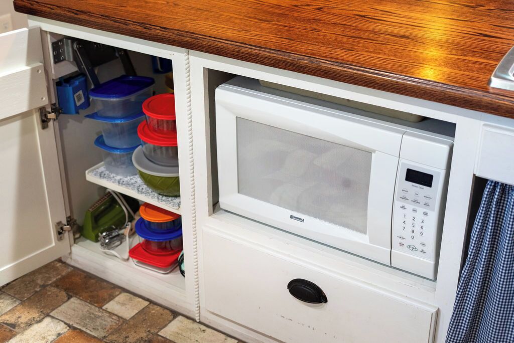 Une cuisine équipée d’un four à micro-ondes encastré et d’étagères de rangement.