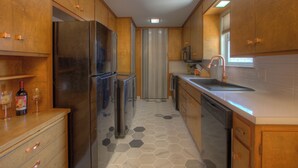 A modern kitchen with wooden cabinets, stainless steel appliances, and a tiled floor. - Mid-Century Modern home in downtown Bartlesville (Bartlesville)
