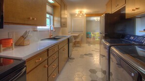 A modern kitchen with wooden cabinets, a stainless steel refrigerator, and a dishwasher. - Mid-Century Modern home in downtown Bartlesville (Bartlesville)