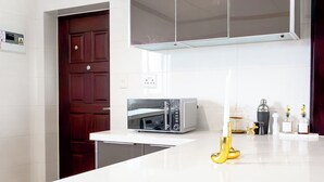 Una cocina moderna con microondas, encimera blanca y una puerta.