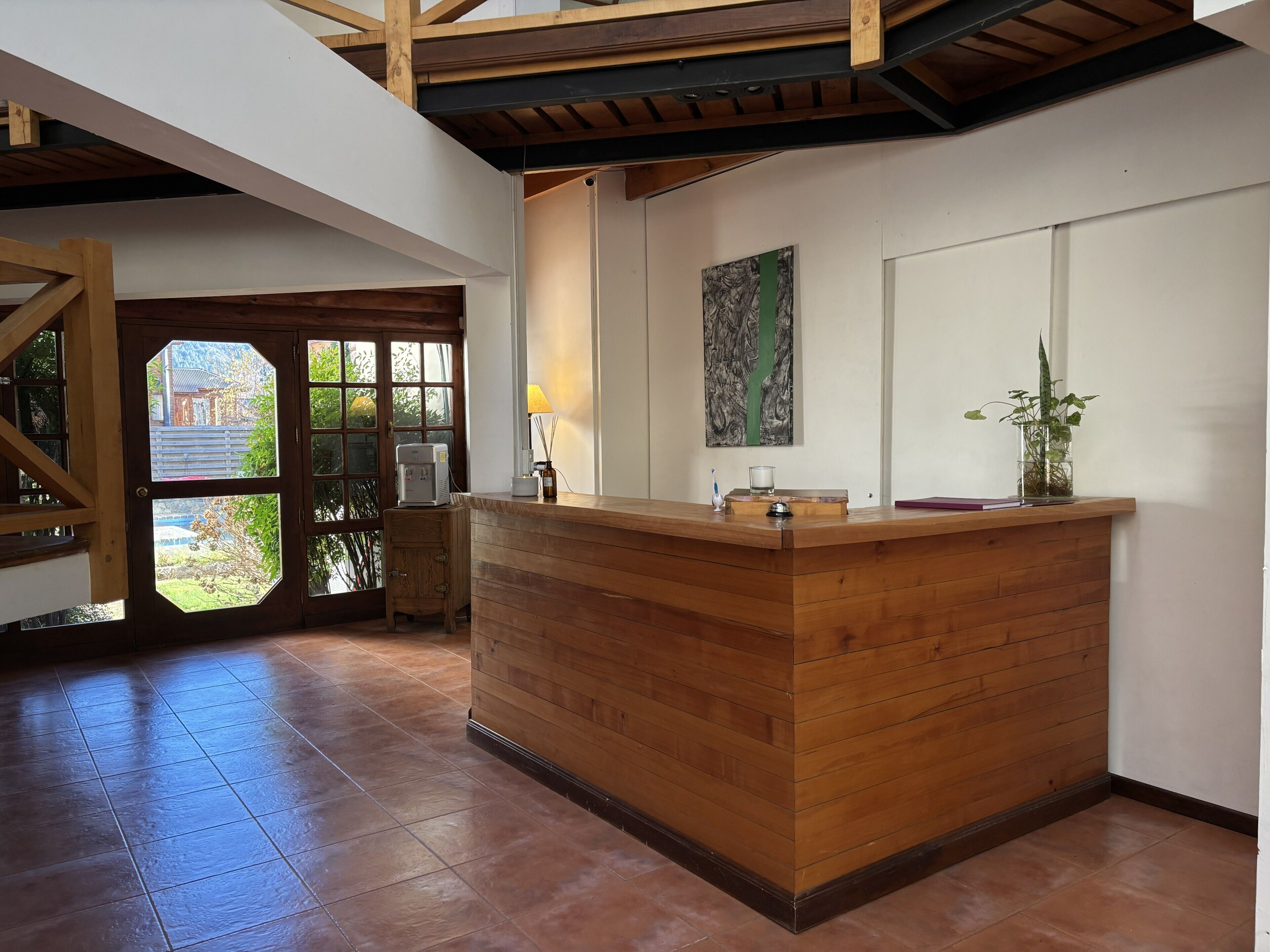 A reception desk with a wooden finish, a water dispenser, a lamp, and a framed artwork on the wall.