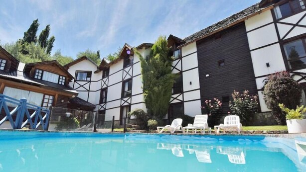 Una piscina con sillones de descanso y un edificio de estructura de madera.