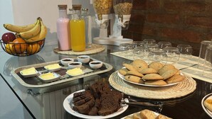 A buffet table with various food items, including cookies, brownies, and a fruit bowl. - Hostería Plaza Mayor  (San Martín de los Andes)