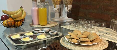 Una mesa de buffet con diversos alimentos, como galletas, brownies y un bol de fruta.