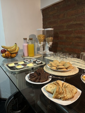 Een buffet met diverse etenswaren, zoals koekjes, brownies en een schaal fruit.
